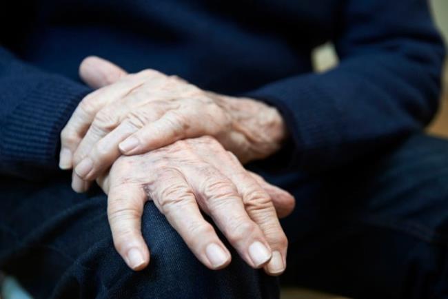 אדם מבוגר מחזיק את ידו הרועדת, בנזהקסול לטיפול בפרקינסון